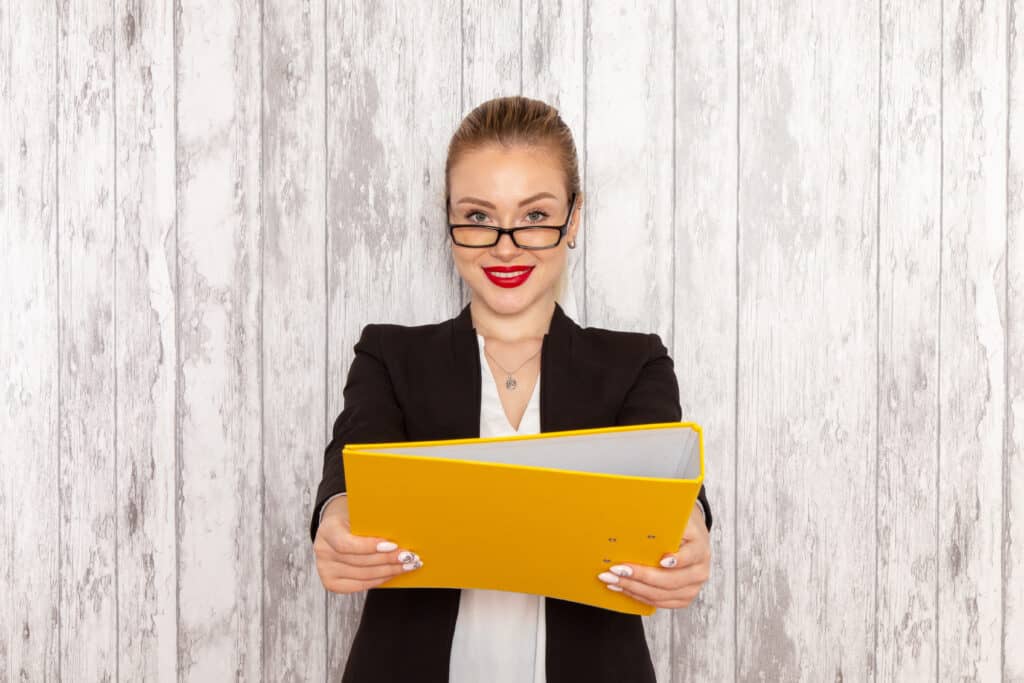 front view young businesswoman strict clothes black jacket holding files documents light white desk